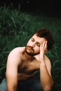 High angle view of shirtless young man crouching on grass