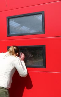 Rear view of woman standing against red wall