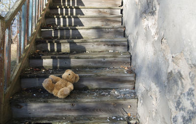 High angle view of teddy bear on wooden steps during sunny day