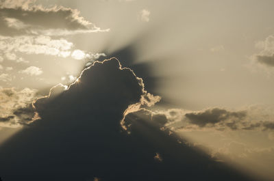 Low angle view of sunlight streaming through clouds