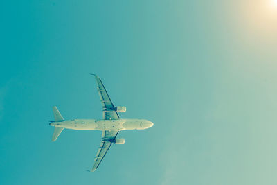 Low angle view of airplane flying against clear blue sky