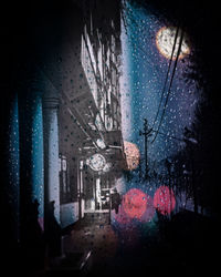 Illuminated buildings seen through wet glass window