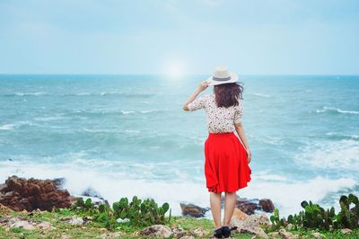 Woman standing on beach against sky