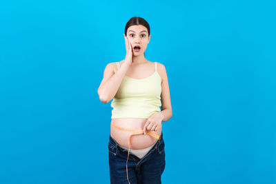 Portrait of young woman against blue background