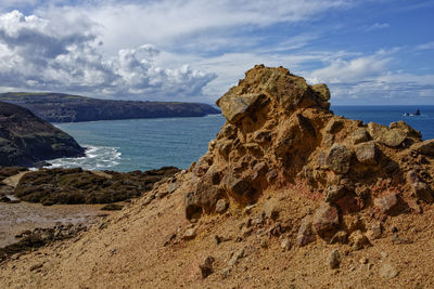 Rock formation on beach against sky