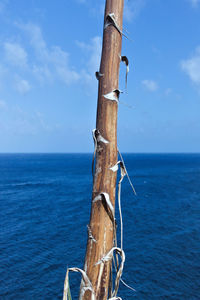 View of wooden post in sea against sky