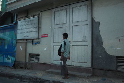 Rear view of man walking by building