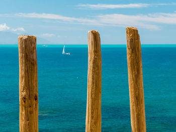 Wooden posts in sea against sky