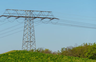 Low angle view of electricity pylon on field against sky