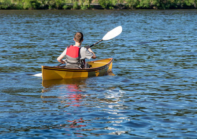 Rear view of man sitting on boat in lake
