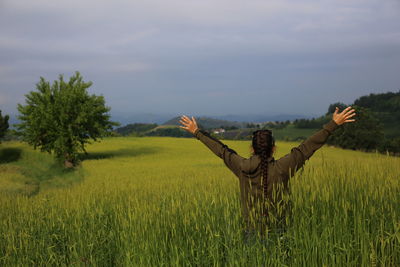 Rear view of woman in agricultural field against sky