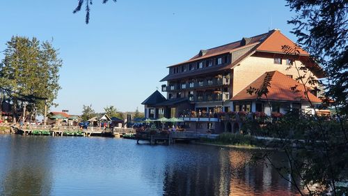 Buildings by river against clear sky