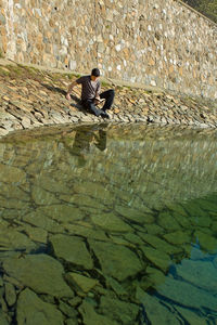 Man sitting on wall by canal