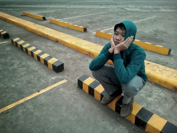 High angle view of thoughtful man crouching at parking lot