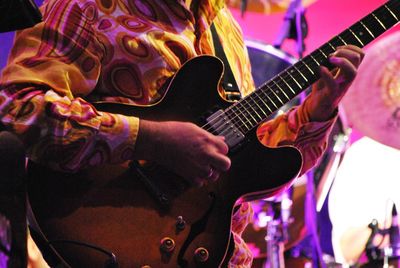 Midsection of guitarist performing during concert