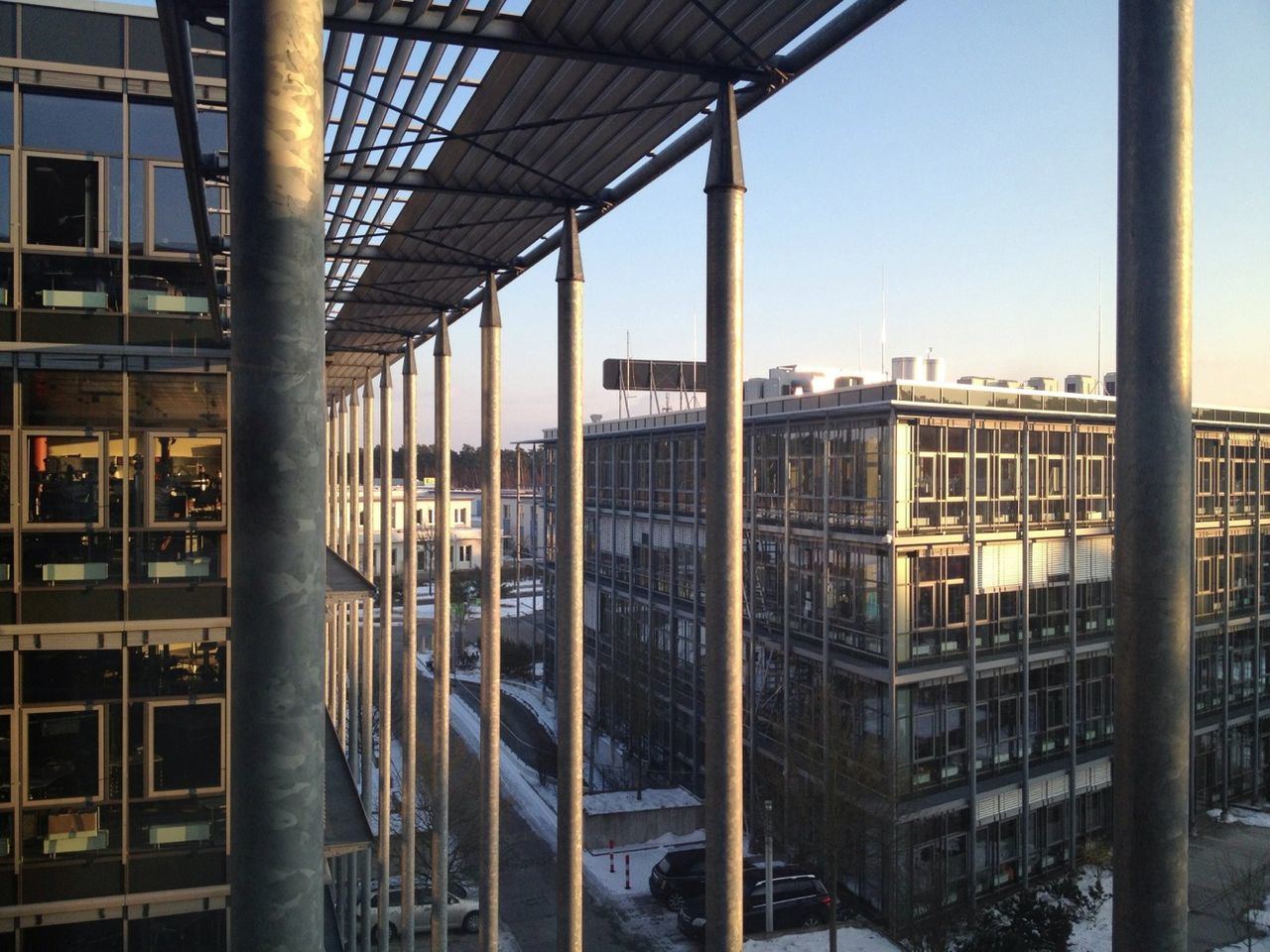 architecture, built structure, building exterior, window, city, building, sky, clear sky, glass - material, indoors, architectural column, day, railing, no people, residential building, low angle view, sunlight, residential structure, modern