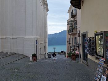 People on street by buildings in town against sky