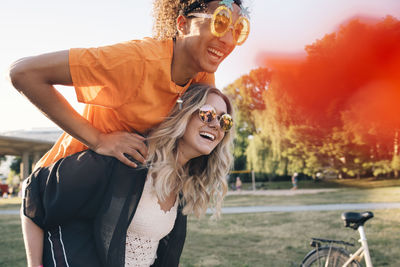 Happy young woman piggybacking man wearing novelty glasses