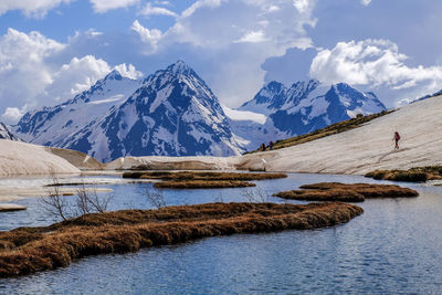 Scenic view of lake and snowcapped mountains against cloudy sky