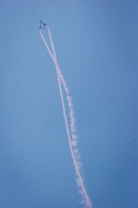 Low angle view of vapor trails in blue sky