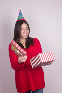 Smiling young woman holding umbrella against white background