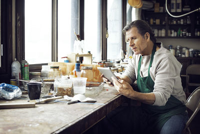 Man using tablet computer while sitting in workshop