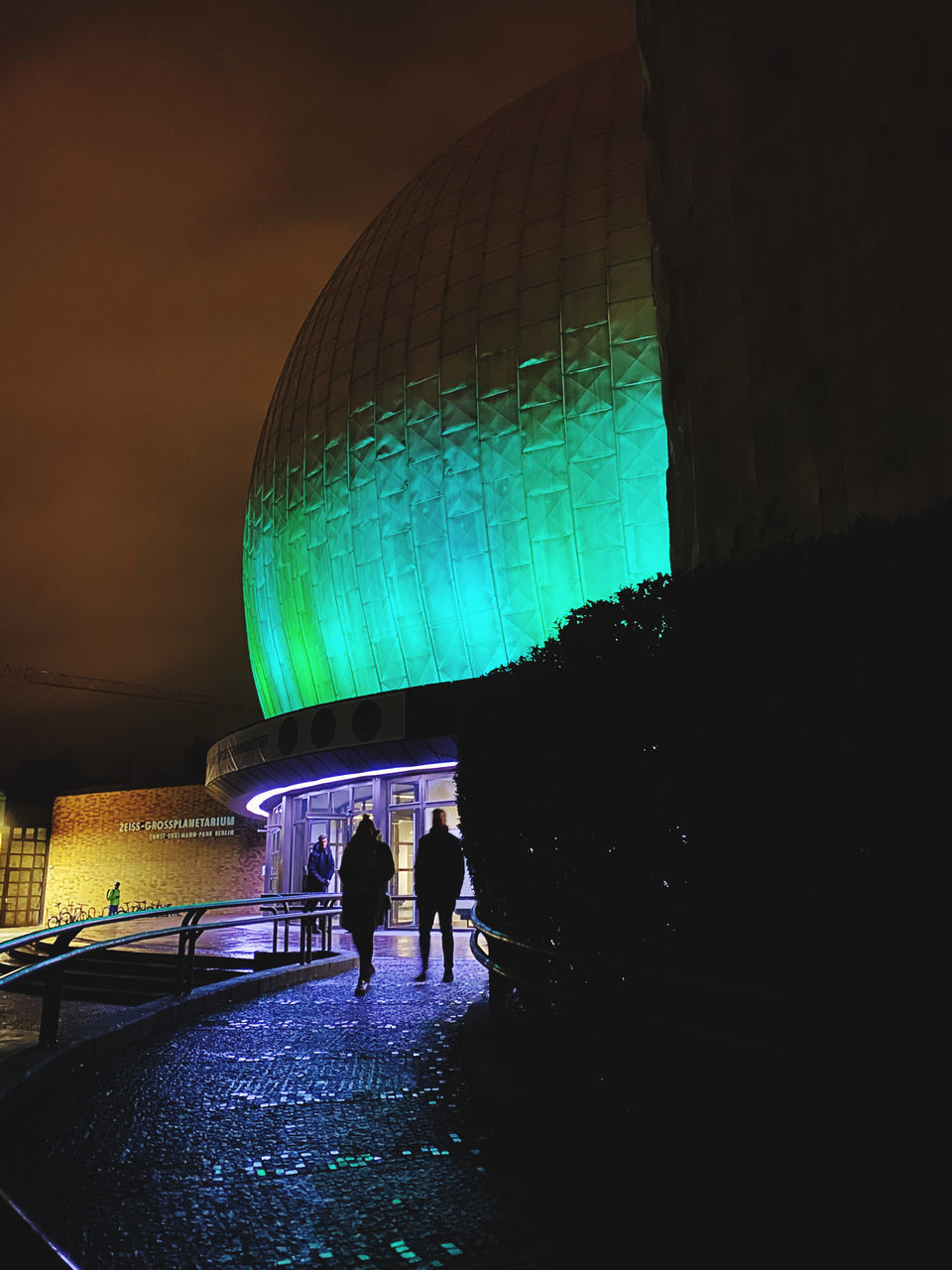 REAR VIEW OF SILHOUETTE PEOPLE WALKING ON ILLUMINATED BUILDING