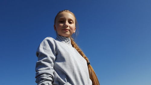 Portrait of smiling young woman against clear blue sky