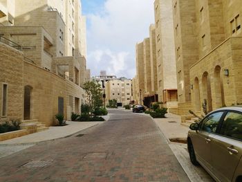 Road amidst buildings in city against sky