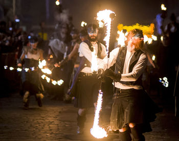 People walking on illuminated street in city at night