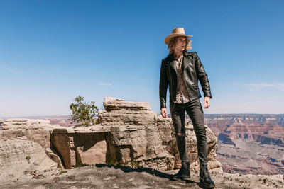 Man standing on rock against blue sky