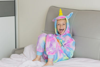 Portrait of cute girl sitting on bed at home