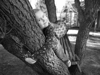 Portrait of young woman by tree trunk