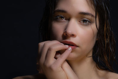 Close-up portrait of beautiful young woman over black background