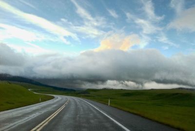 Country road against cloudy sky
