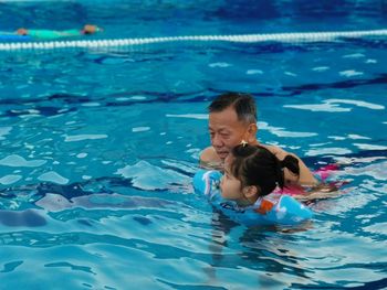 High angle view of senior man with granddaughter in swimming pool