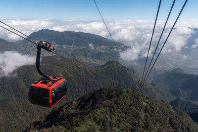 Overhead cable car over mountains against sky