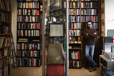 Portrait of confident man with arms crossed standing in library