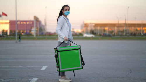 Side view of woman standing on road in city