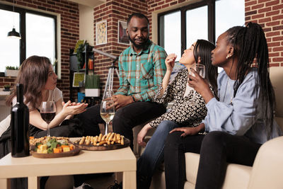 Portrait of smiling friends using mobile phone while sitting at home