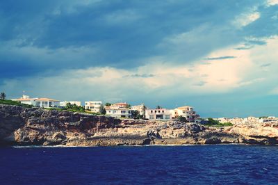 Buildings by sea against sky in town
