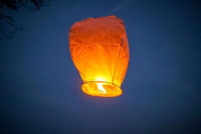 Low angle view of illuminated lantern against blue sky