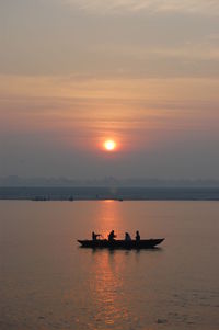 Silhouette boat in sea against sky during sunset