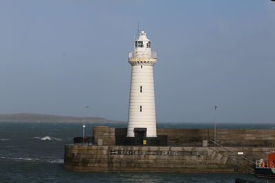 Lighthouse by sea against sky