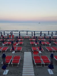 Chairs and tables on beach against clear sky