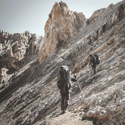 Rear view of man walking on rock against sky