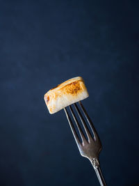 Close-up of marshmallow on fork against black background