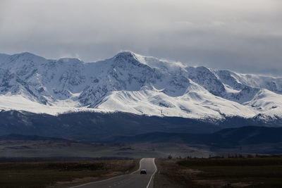 Car on country road against snowcapped mountains