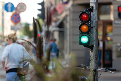 Illuminated road signal with woman standing in background