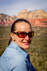 Side view portrait of smiling woman wearing sunglasses at desert during sunny day